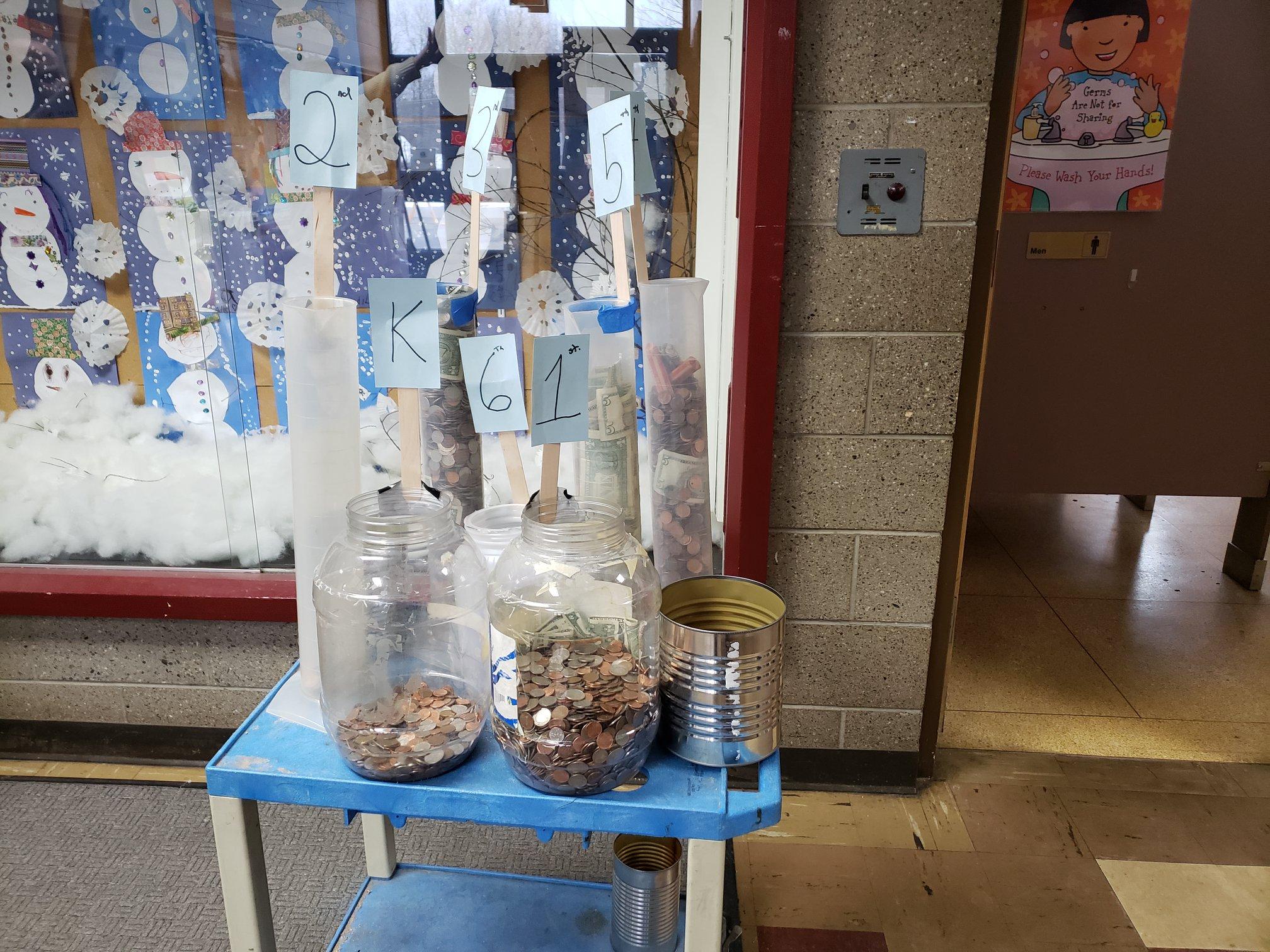 table holding jars and cans partially filled with coins